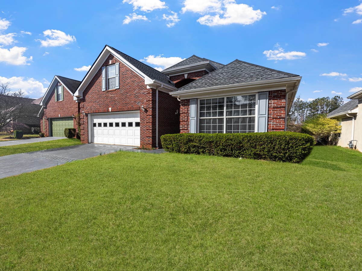 Lovely red brick suburban house with a well-maintained lawn under a bright blue sky.