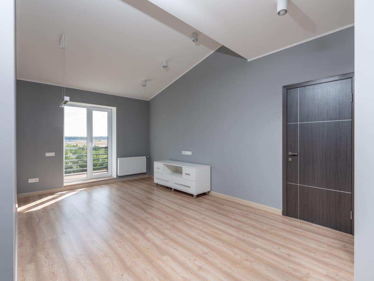 Bright and empty modern room with hardwood floors and large window view.